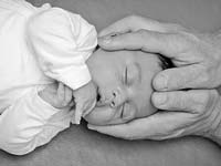 Nouveau né endormi les deux mains du chiro sur sa tête image nb